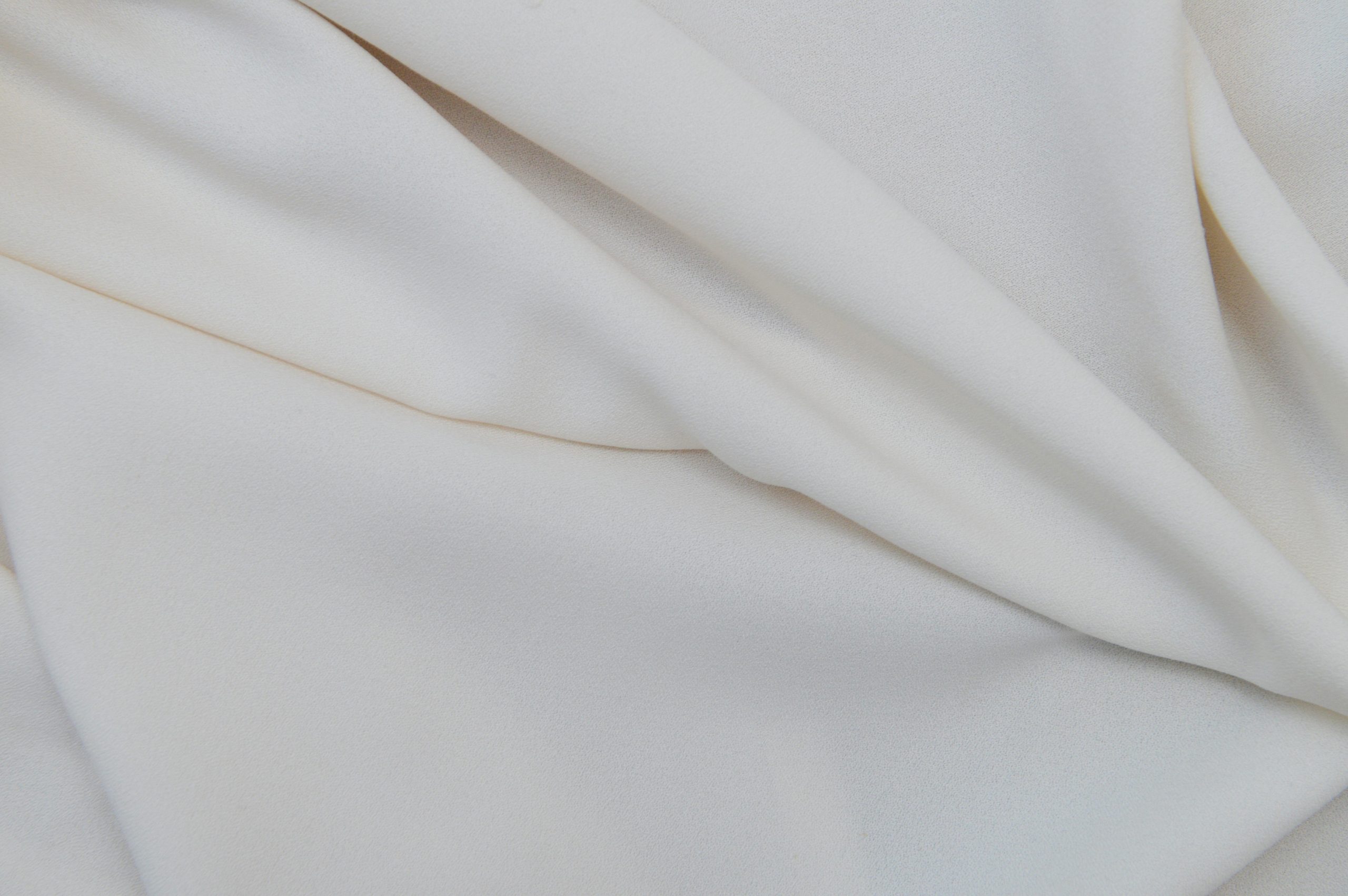 Close-up of elegant white fabric with smooth folds and texture details.